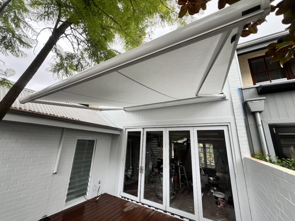 All white retractable motorised folding arm awning installed on the building facade over the courtyard in Subiaco, Perth WA
