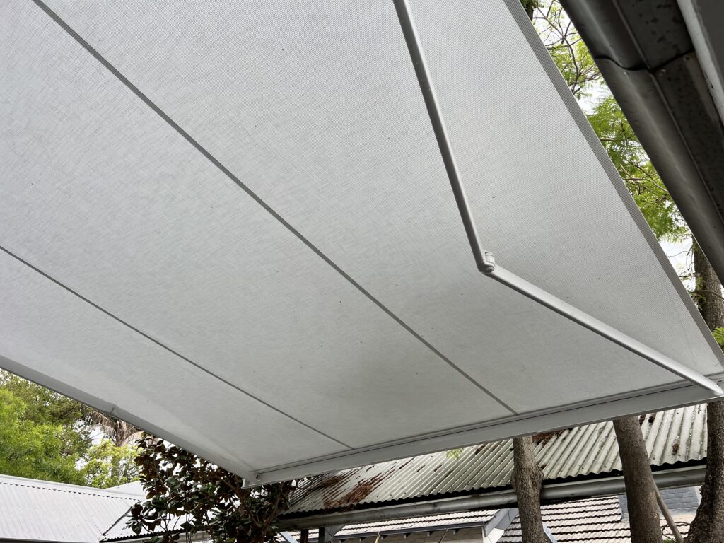 All white retractable motorised folding arm awning installed over the backyard in Subiaco, Perth WA