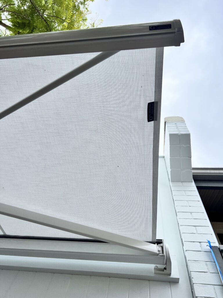 All white retractable motorised folding arm awning installed on the building facade over the courtyard in Subiaco, Perth WA