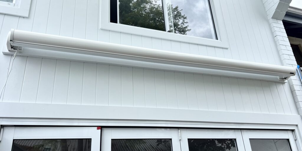 All white retractable motorised folding arm awning installed on the building facade over the courtyard in Subiaco, Perth WA
